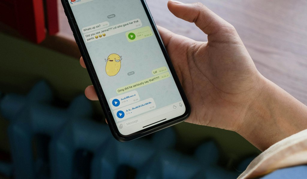Mão segurando smartphone com aplicativo de mensagens aberto, representando Dark Social e tráfego invisível