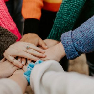 Grupo de pessoas com mãos unidas no centro representando comunidade engajada e marketing de tribos