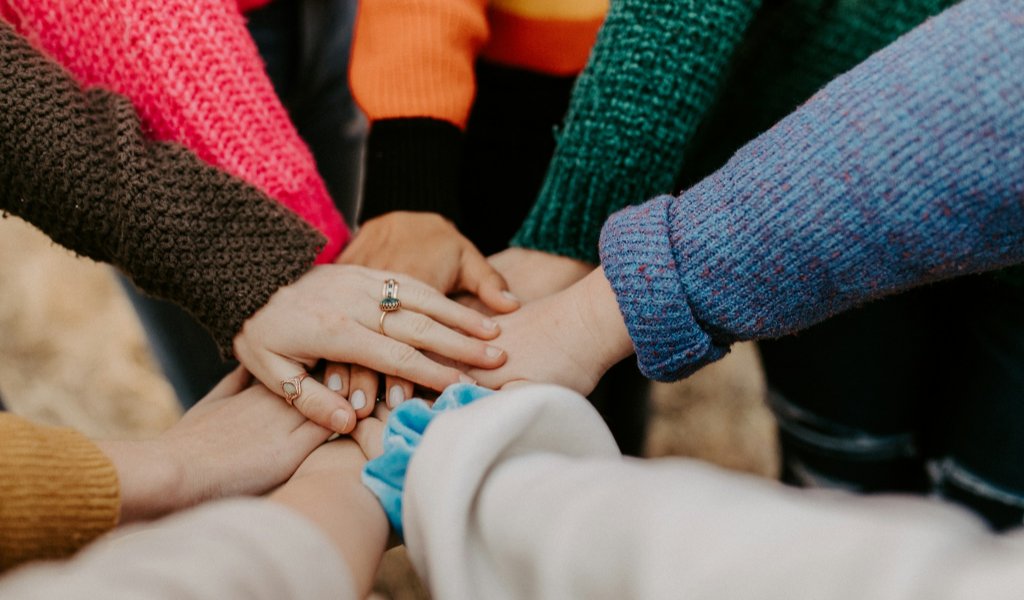 Grupo de pessoas com mãos unidas no centro representando comunidade engajada e marketing de tribos