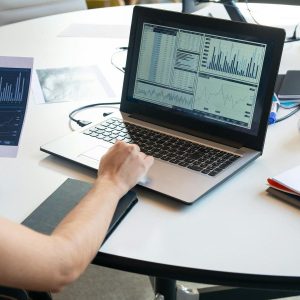 Pessoa analisando gráficos e dados em laptop, ilustrando estratégia de Programmatic SEO