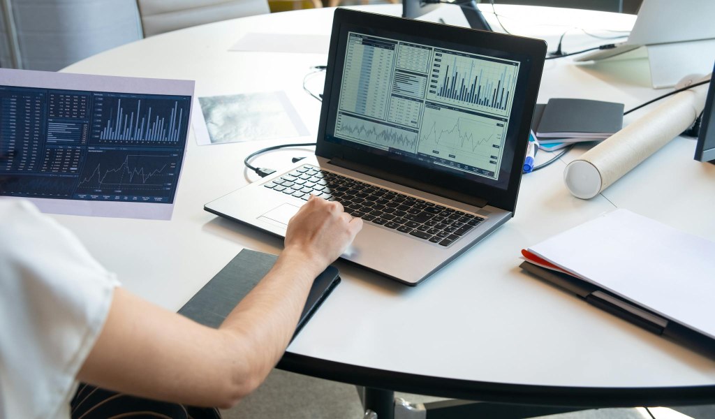 Pessoa analisando gráficos e dados em laptop, ilustrando estratégia de Programmatic SEO