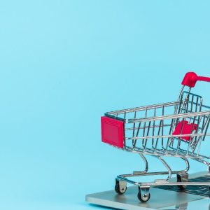 Carrinho de compras ao lado de um notebook representando compras online
