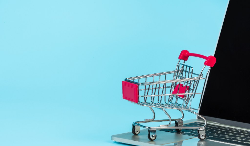 Carrinho de compras ao lado de um notebook representando compras online