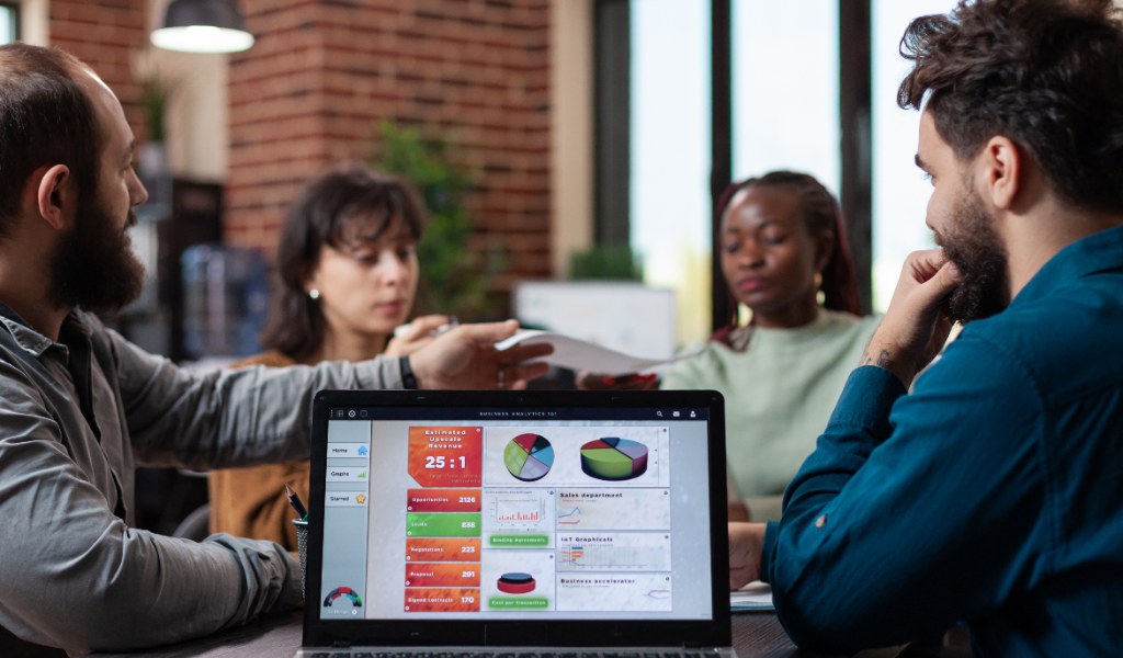Equipe de marketing e vendas analisando gráficos de receita em um notebook